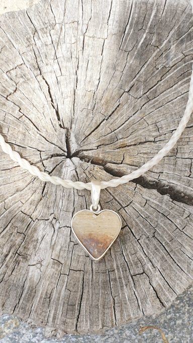 Collar con un colgante en forma de corazón sobre una superficie de madera.